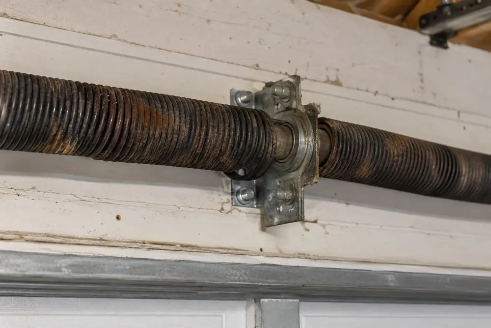 Aged torsion spring with surface corrosion being visually inspected