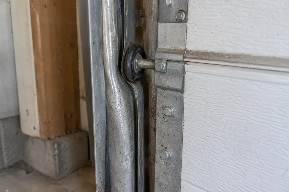 Garage door roller pressed against a bent vertical track