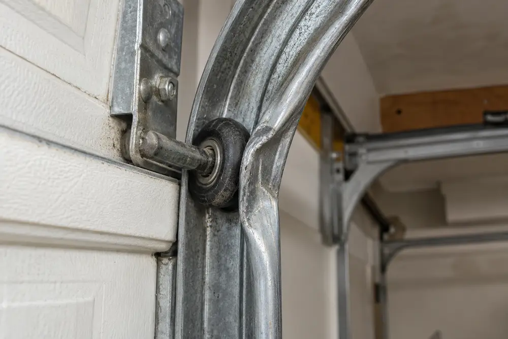 Garage door roller contacting a bent section of track