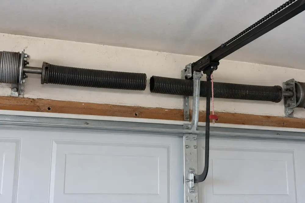 Visible gap in a broken torsion spring above a closed residential garage door