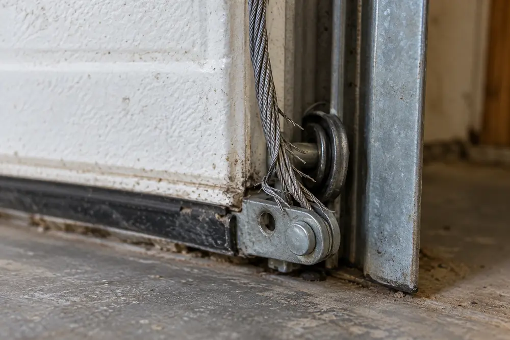 Close view of broken wire strands on a garage door lift cable