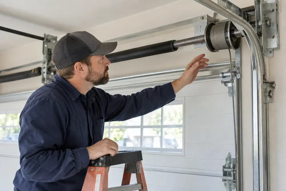 Technician visually inspecting garage door cable seating on a drum