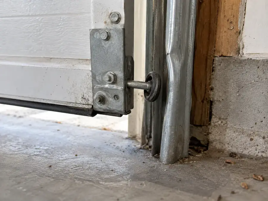 Garage door roller sitting outside a bent vertical track during inspection