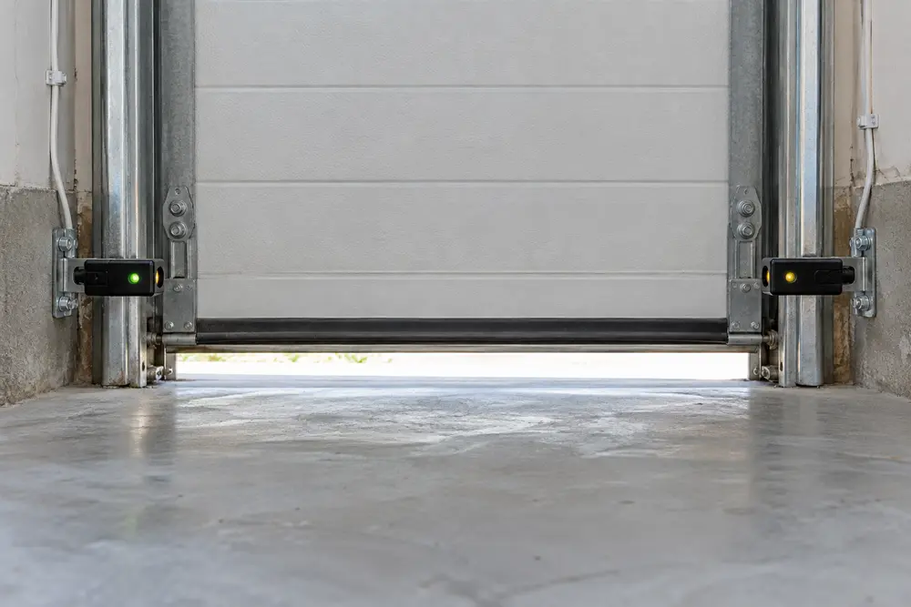 Garage door safety sensors mounted near the floor on both sides of the opening
